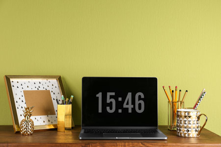 Modern workplace with laptop and golden decor on desk near wall. Stylish interior designの写真素材