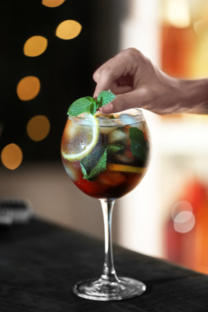 Woman preparing fresh alcoholic cocktail with lemon and mint at bar counter, closeupの写真素材