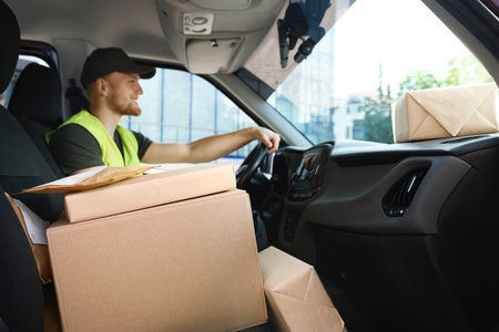 Young courier with parcels in delivery carの写真素材