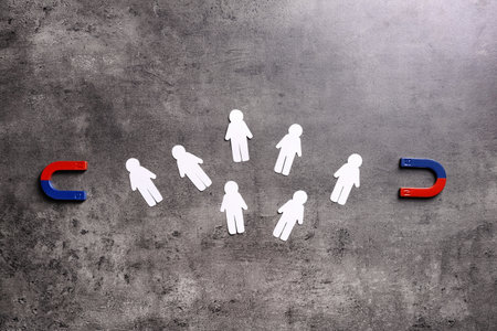 Magnet attracting paper people on gray stone background, flat lay. marketing conceptの写真素材