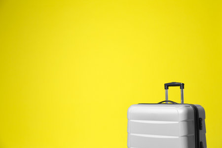 Stylish gray suitcase on yellow background. Space for textの写真素材