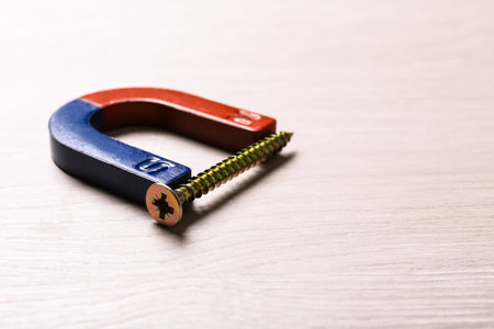 Magnet attracting screw on light wooden background, closeupの写真素材