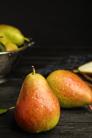 Ripe juicy pears on dark wooden table against black background. Space for textの写真素材