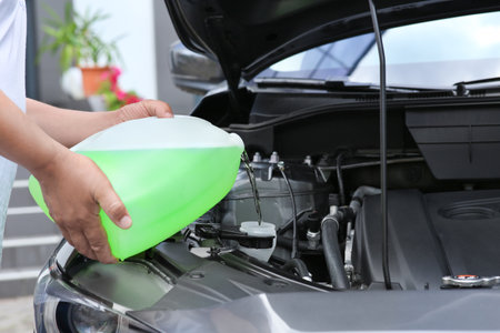 Man pouring liquid from plastic canister into car washer fluid reservoir, closeupの写真素材