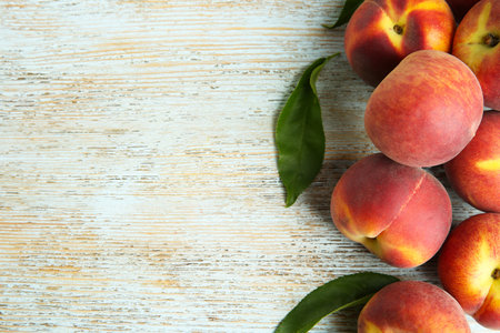 Fresh juicy peaches and leaves on blue wooden table, flat lay. Space for textの写真素材