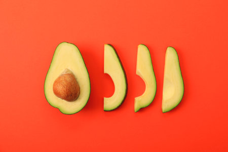 Flat lay composition with avocado slices on red background