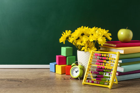 Vase of flowers, books and toys on wooden table near green chalkboard, space for text. teacher's dayの写真素材