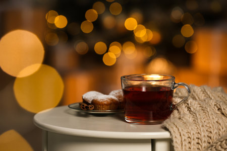 Cup of hot tea on white table against blurred lights, space for text. Cozy winterの写真素材