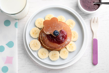 Tasty pancakes served with jam and milk on white wooden table, flat lay. creative idea for kids breakfastの写真素材