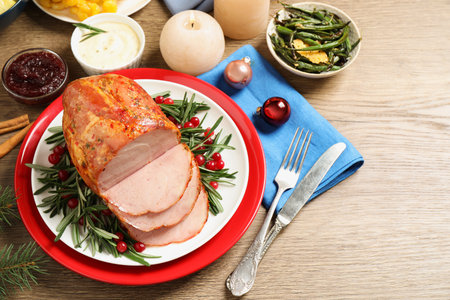 Delicious Christmas ham served with garnish on wooden table, above viewの写真素材