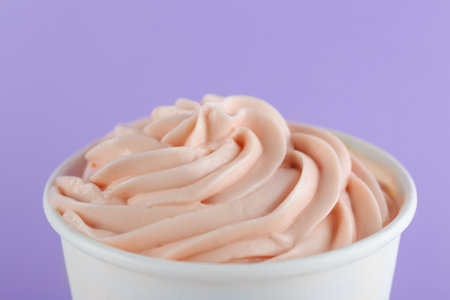Cup with tasty frozen yogurt on violet background, closeupの写真素材