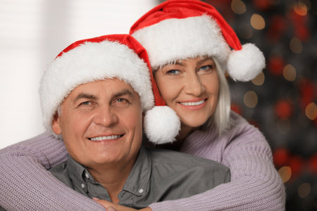 Happy mature couple in Santa hats at home. christmas celebrationの写真素材