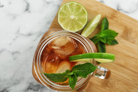Mason jar of delicious iced tea on marble table, top view
