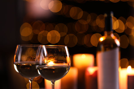 Glasses of wine and blurred view of burning candles on backgroundの写真素材