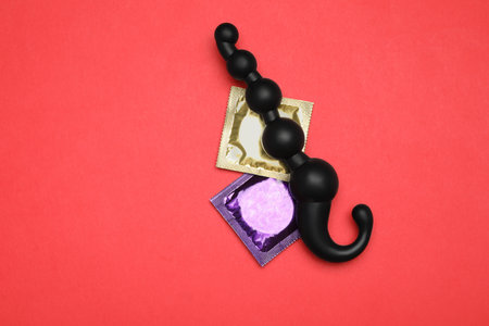 Anal ball beads and condoms on red background, top view. sex gamesの写真素材