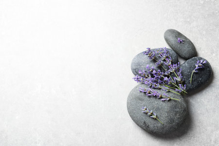 Spa stones and lavender flowers on gray table, flat lay. Space for textの写真素材