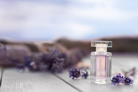 Bottle of luxury perfume and lavender flowers on white wooden table outdoors. Space for textの写真素材