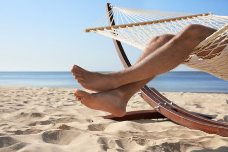 Young man relaxing in hammock on beach, closeupの写真素材