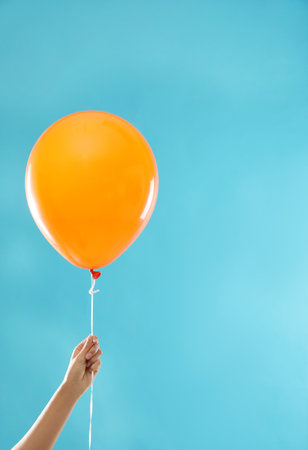 Woman holding orange balloon for Halloween party on blue backgroundの写真素材