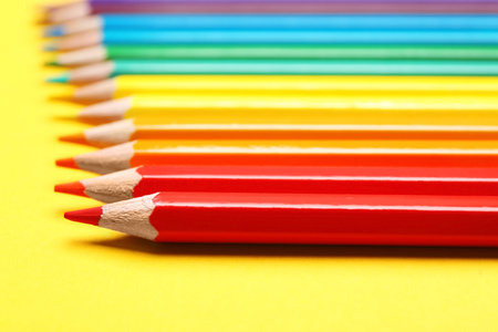 Different color pencils on yellow background, closeup