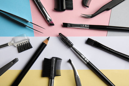Set of professional eyebrow tools on color background, flat lay
