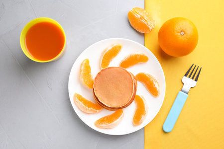 Tasty pancakes served with orange and juice on gray table, flat lay. creative idea for kids breakfastの写真素材