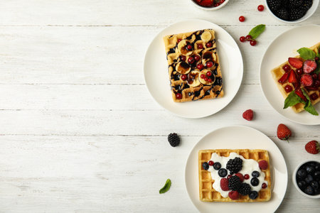 Flat lay composition with delicious waffles and fresh berries on white wooden table. Space for textの写真素材