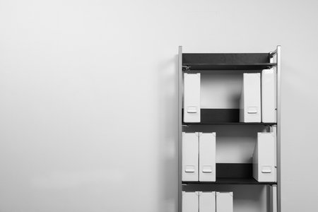 Shelving unit with folders near white wall, space for textの写真素材