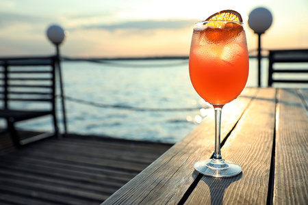 Glass of fresh summer cocktail on wooden table outdoors at sunset. Space for textの写真素材