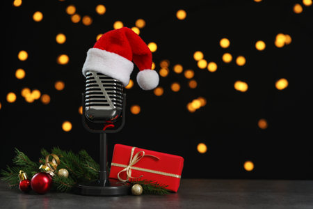 Microphone with Santa hat and decorations on gray table against blurred lights, space for text. christmas musicの写真素材