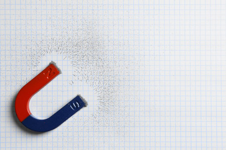 Magnet attracting iron powder on squared paper, top view. Space for textの写真素材
