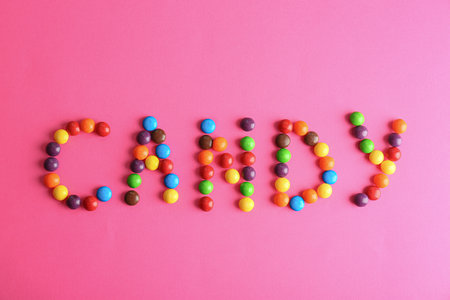 Word CANDY made of different glazed candies on pink background, flat layの写真素材