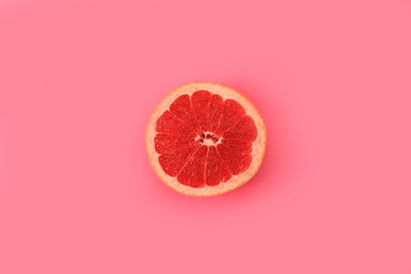 Half of delicious juicy grapefruit on pink background, top viewの写真素材