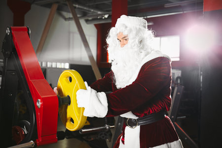 Young Santa Claus with weight plate in modern gymの写真素材