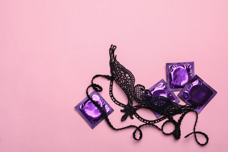 Lace mask and condoms on pink background, top view with space for text. sex gamesの写真素材