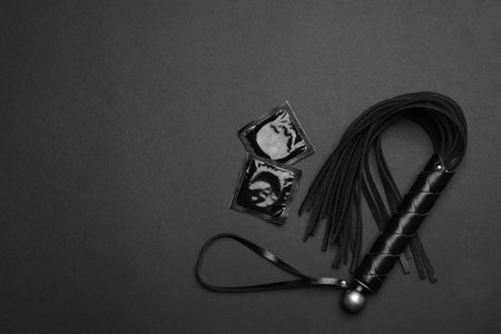 Whip and condoms on black background, top view with space for text. sex gamesの写真素材