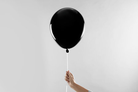 Woman holding black balloon for Halloween party on light gray background, closeupの写真素材