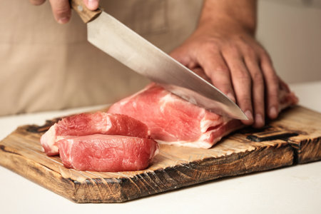 Man cutting fresh raw meat on table, closeupの写真素材