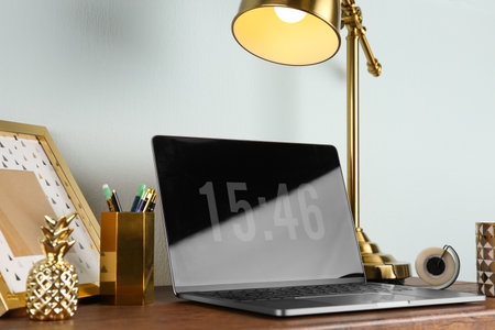 Modern workplace with laptop and golden decor on desk near wall. Stylish interior designの写真素材
