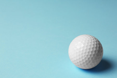 Golf ball on light blue background. Space for textの写真素材