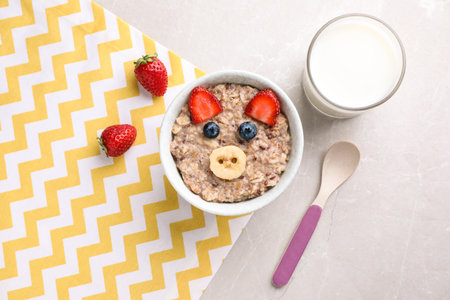 Tasty porridge served with berries and milk on marble table, flat lay. creative idea for kids breakfastの写真素材