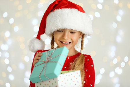 Happy little child in Santa hat with gift box against blurred festive lights. christmas celebrationの写真素材
