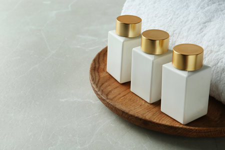 Wooden tray with cosmetic bottles and towel on light gray marble table, space for text. spa treatmentの写真素材
