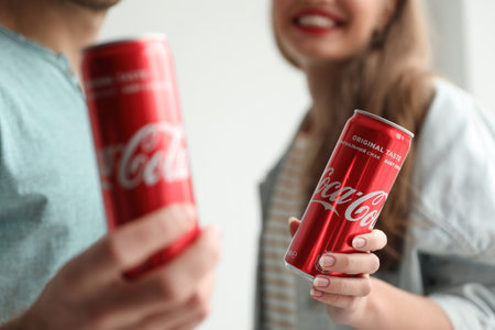 MYKOLAIV, UKRAINE - NOVEMBER 28, 2018: Young couple with Coca-Cola cans indoors, closeup