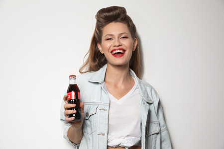 MYKOLAIV, UKRAINE - NOVEMBER 28, 2018: Young woman with bottle of Coca-Cola on white backgroundのeditorial素材