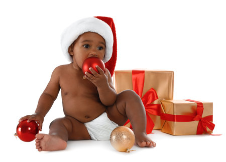 Cute African-American baby wearing Santa hat with Christmas gifts on white backgroundの写真素材