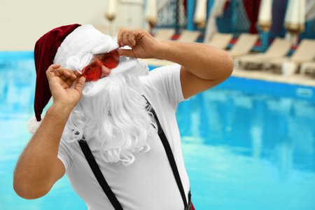 Authentic Santa Claus wearing sunglasses near pool at resortの写真素材