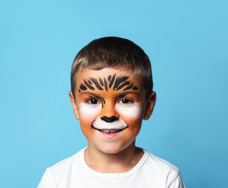 Cute little boy with face painting on blue backgroundの写真素材