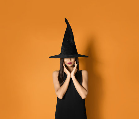 Beautiful woman wearing witch costume for Halloween party on yellow background, space for textの写真素材