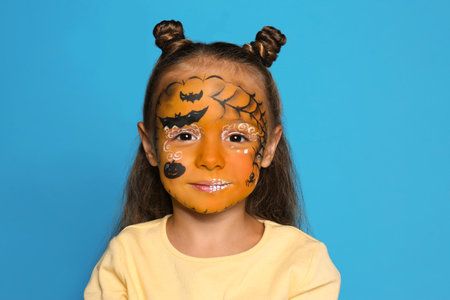 Cute little girl with face painting on blue backgroundの写真素材